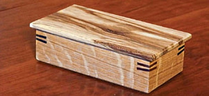 Boîte à bijoux en bois rectangulaire finie, refermée et posée sur une table