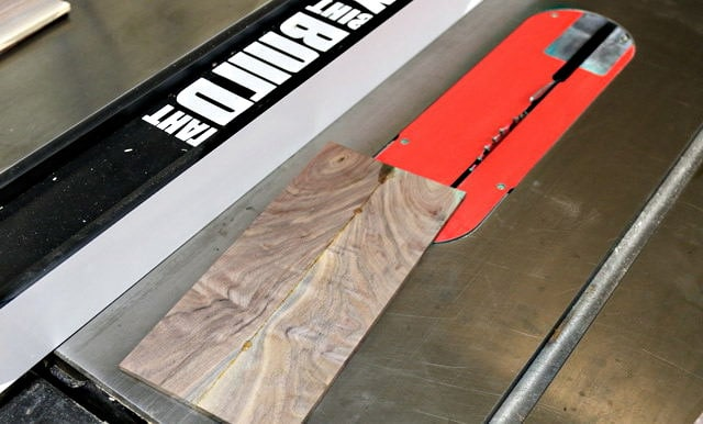 Une planche de bois de noyer brut est coupée dans sa longueur